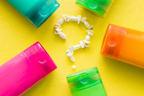 Assorted colorful soap containers with soap beads forming a question mark on yellow background