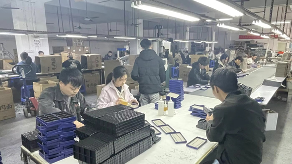 Packaging production factory with workers assembling custom boxes