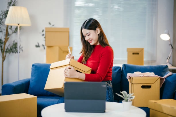 Small business entrepreneur packing order into cardboard box for shipment