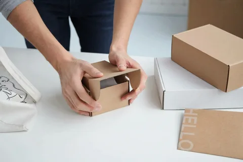 Hands folding and assembling a small kraft shipping box