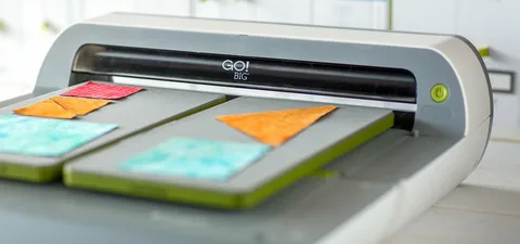 Close-up view of electric die cut machine cutting fabric into triangle and square shapes