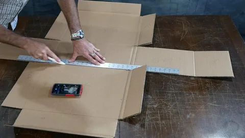 Person measuring and cutting corrugated board for building a custom-sized box