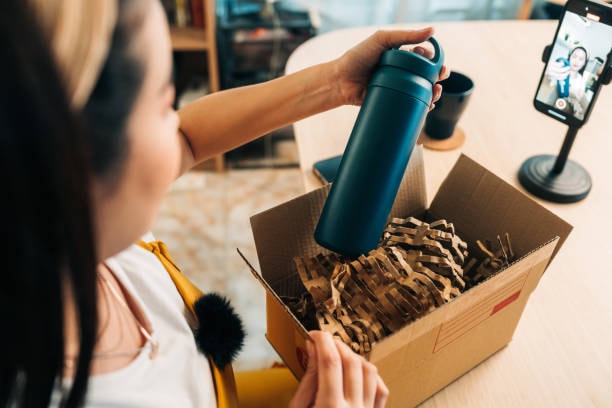 Influencer recording unboxing of a PR package containing a tumbler while engaging with followers