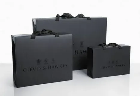 Elegant black shopping bags with ribbon handles used for high end clothing packaging