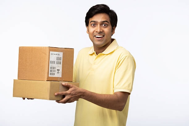 Smiling man in yellow shirt holding cardboard packages for t shirt delivery