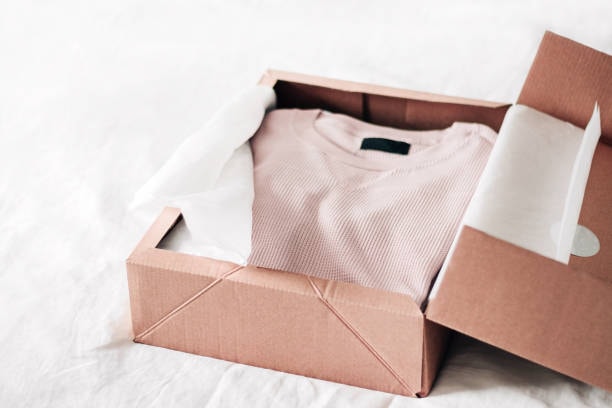 Ribbed pink T shirt packaged in brown cardboard box with white tissue paper