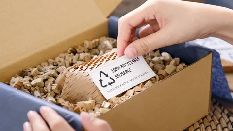 Hand holding 100% recyclable reusable tag in cardboard shipping box