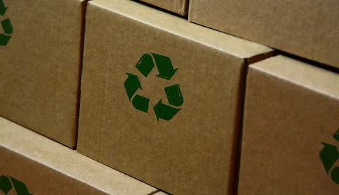 Stacked brown cardboard boxes printed with recycle logos