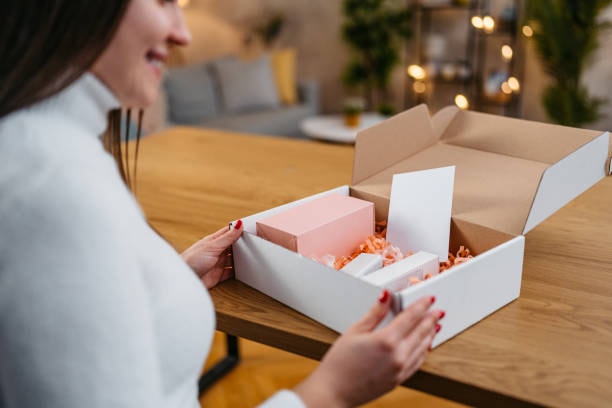 Smiling woman opening a PR package filled with custom beauty products and brand inserts
