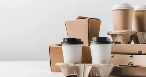 Paper coffee cups and brown takeaway boxes used for eco-friendly bagged packaged goods in food service.