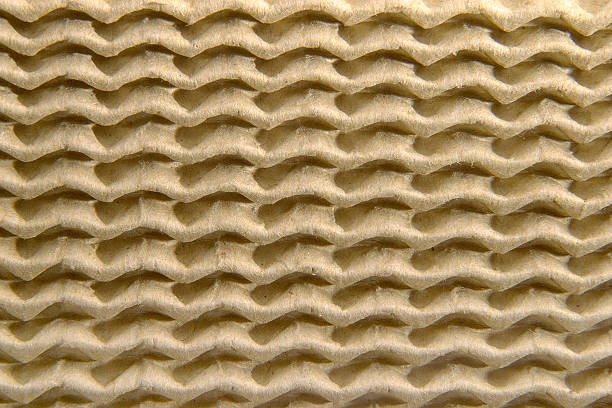 Detailed texture of corrugated cardboard fluting, highlighting wavy inner layer structure for cushioning.