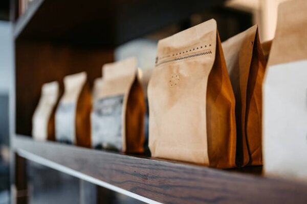 Kraft paper coffee packaging bags arranged on wooden shelf for sale.