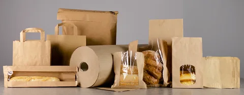 Kraft paper bags with transparent windows displaying bakery and bread products in eco-friendly packaging.
