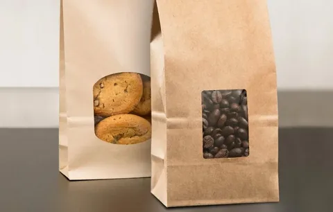 Kraft paper bag packaging with transparent window for displaying coffee beans and baked goods.