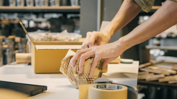 Hands packing product with protective corrugated cardboard box and wrapping