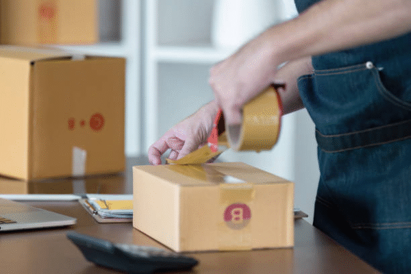 DIY small business packaging process with sealing tape and kraft box ready for delivery.