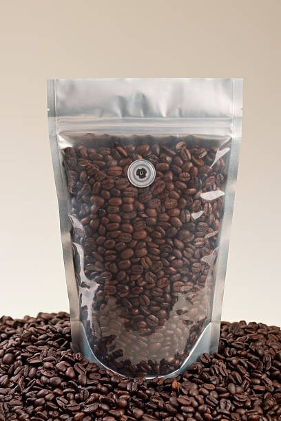 Transparent stand-up pouch for coffee beans featuring degassing valve and zip lock.