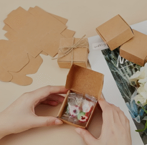 Person folding a small kraft apparel box to demonstrate sustainable, custom packaging for fashion products.