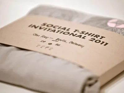 Kraft paper packaging sleeve wrapping a folded t-shirt with minimalist printed design.