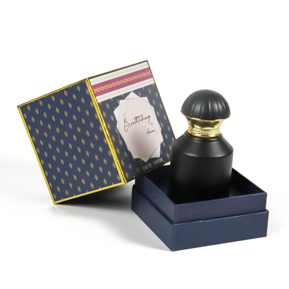 Deep blue folding carton with gold geometric pattern and handwritten brand name, housing a matte black perfume bottle with gold cap—demonstrating artistic custom packaging that tells a brand story.