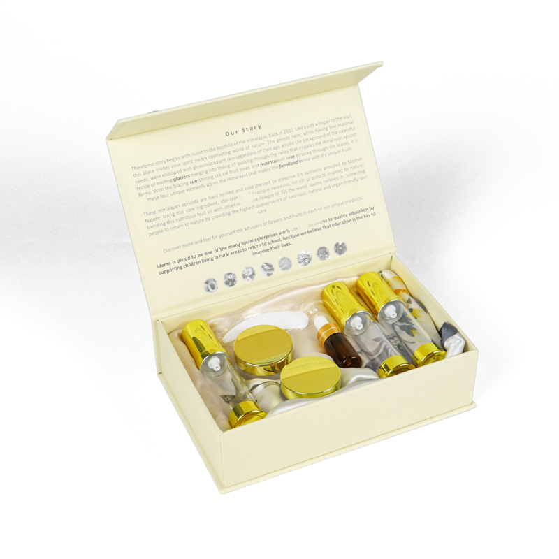 Cream-colored rigid box with printed brand story on inner lid, containing multiple golden tubes and jars—showcasing high-end cosmetic packaging designed for premium unboxing experience.