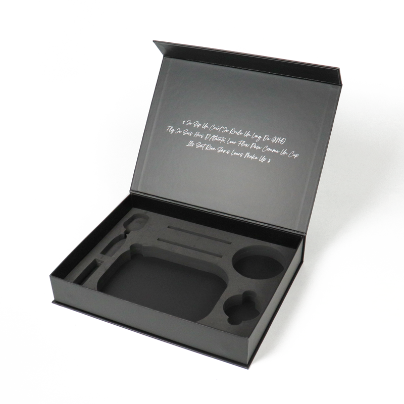 Open black rigid box with custom foam insert and handwritten-style text inside lid, showcasing high-end packaging with precise internal cut-outs for product protection.