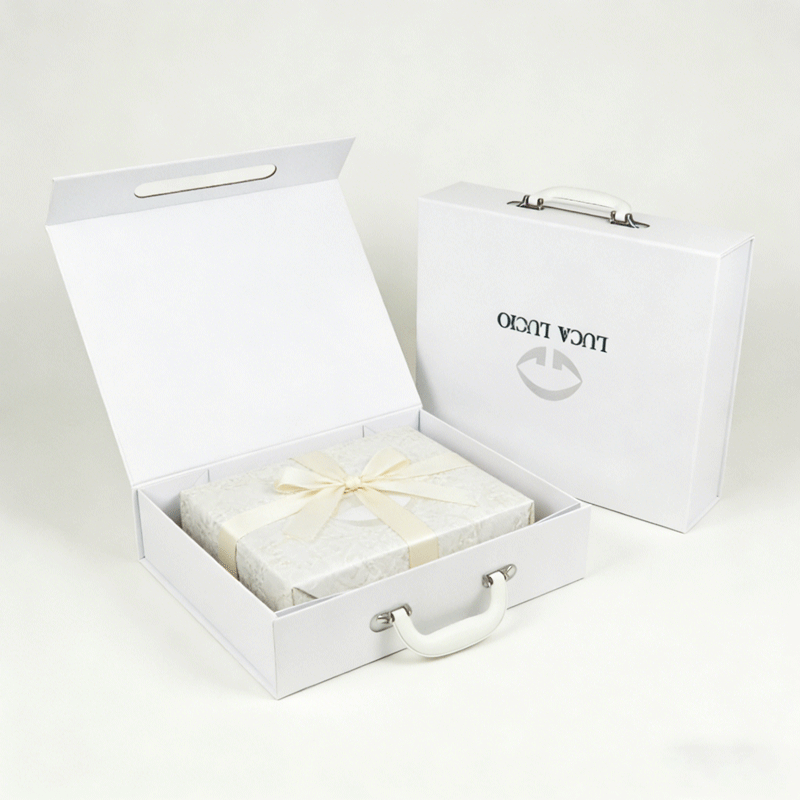 White rigid box with handle, open to reveal an inner gift box tied with a ribbon, showcasing elegant custom apparel packaging with branding.