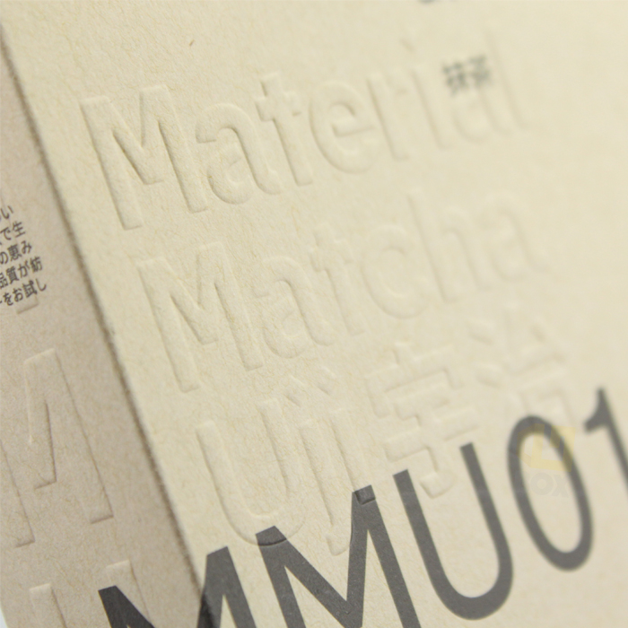 Close-up of raised text "Material Matcha" on a natural paper surface, showcasing blind embossing that creates depth and texture without any added color or foil.