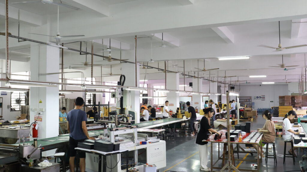 Interior view of a busy packaging factory with workers assembling boxes on production lines—illustrating how efficient workflows and large-scale operations help meet MOQ requirements and reduce per-unit costs while managing lead time across multiple orders.
