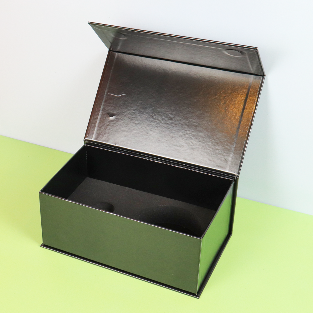 A dark green metallic rigid box with a hinged lid and black foam inserts, open to reveal product compartments—ideal for protecting delicate garments or premium accessories during shipping and display.