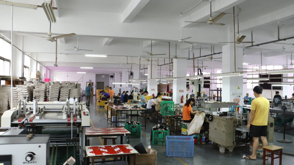 Workers assemble custom folding cartons and rigid boxes on long production lines in a large-scale packaging factory—showcasing the infrastructure required to support omnichannel brands with consistent quality across different packaging formats for online and in-store use.