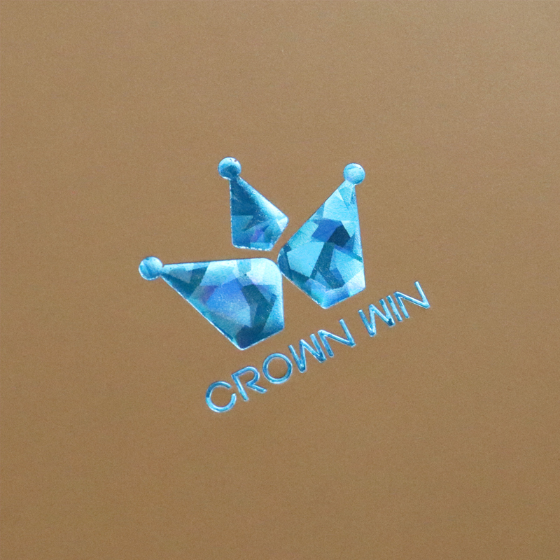 Close-up of a blue holographic foil-stamped logo reading "CROWN WIN" on a matte brown background, showcasing iridescent effects.