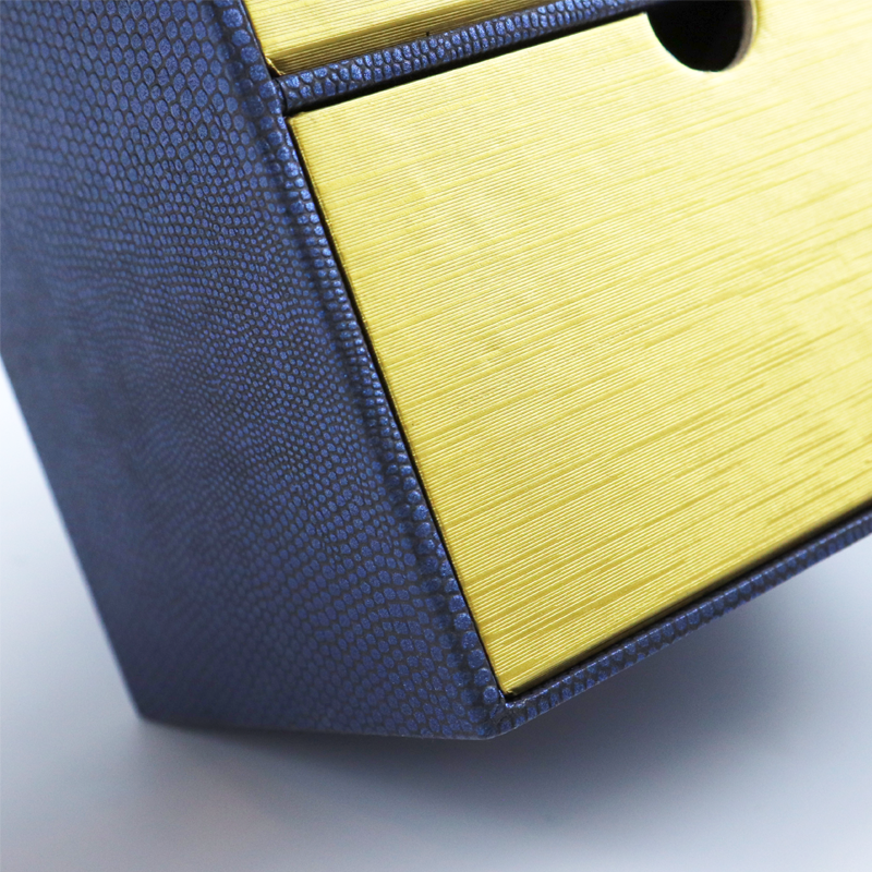 Detail shot of a blue and yellow rigid box featuring contrasting textures: one side with a dotted leather-like pattern, the other with horizontal wood grain finish.