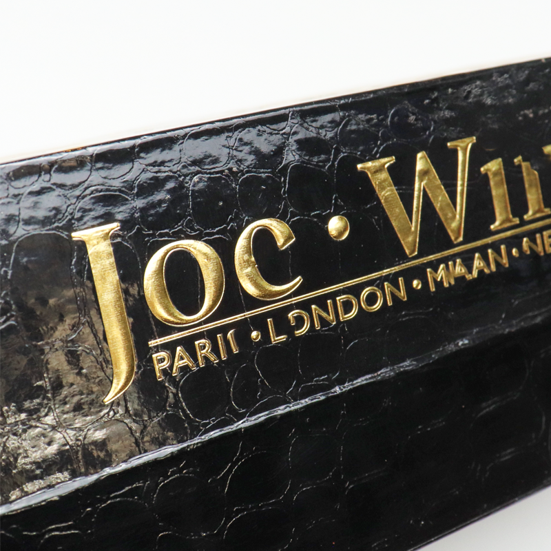 Close-up of a black rigid box featuring crocodile-textured soft touch lamination and raised gold foil lettering, showcasing high-end finishes for luxury branding.