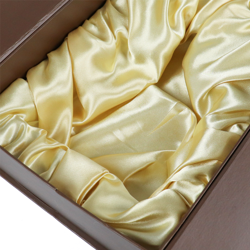 Close-up view of a luxurious golden satin interior lining inside a custom rigid box—highlighting the tactile quality and protective function that contribute significantly to overall packaging cost and perceived product value.