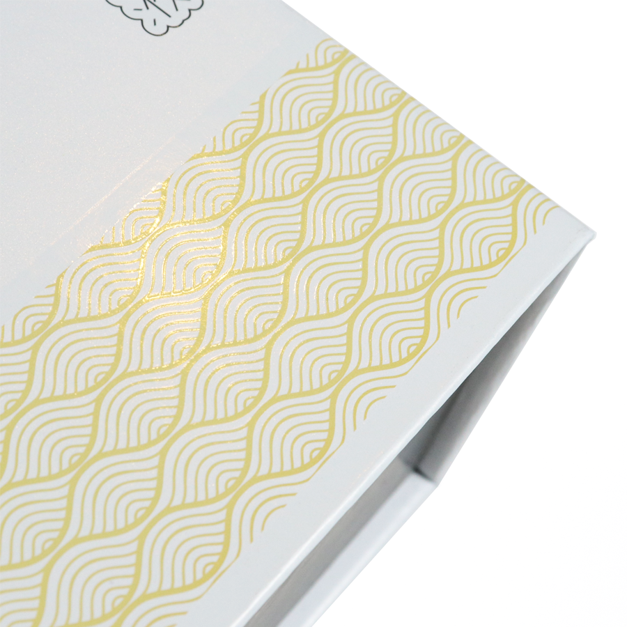 A close-up of a white folding carton featuring an elegant gold foil wave pattern—highlighting how sustainable packaging can maintain premium branding while using eco-conscious materials like recycled or FSC-certified paper.