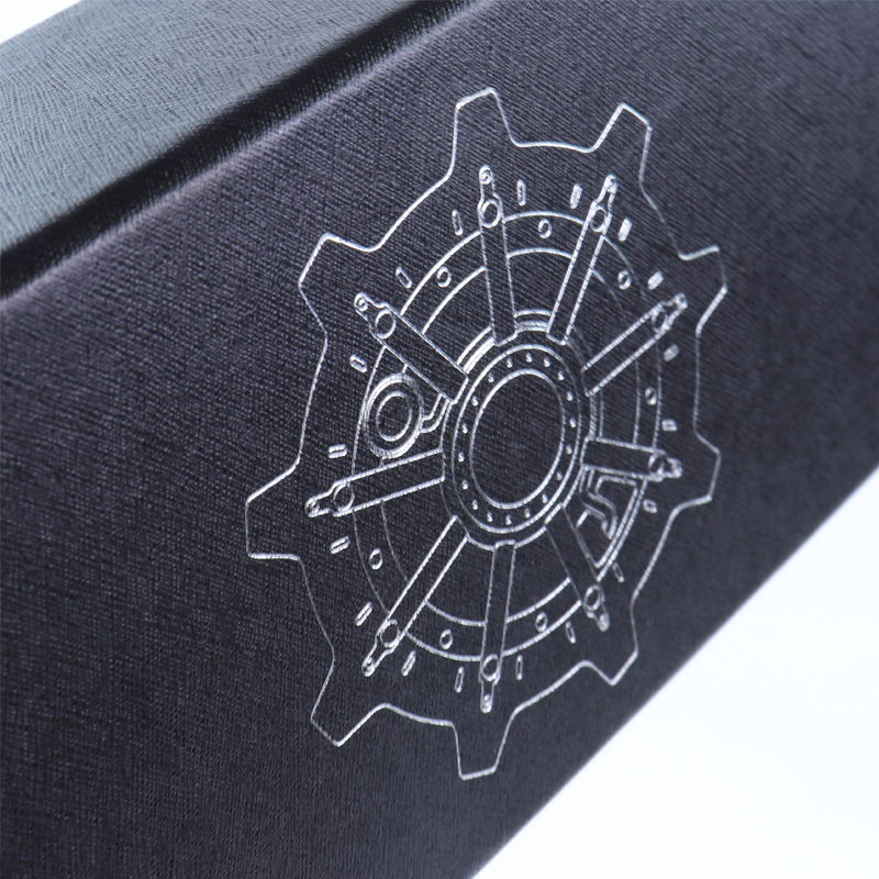 Black textured box with a silver-outlined gear pattern created using clear Spot UV coating, showcasing fine-line detail and subtle gloss enhancement for industrial or tech-themed branding.