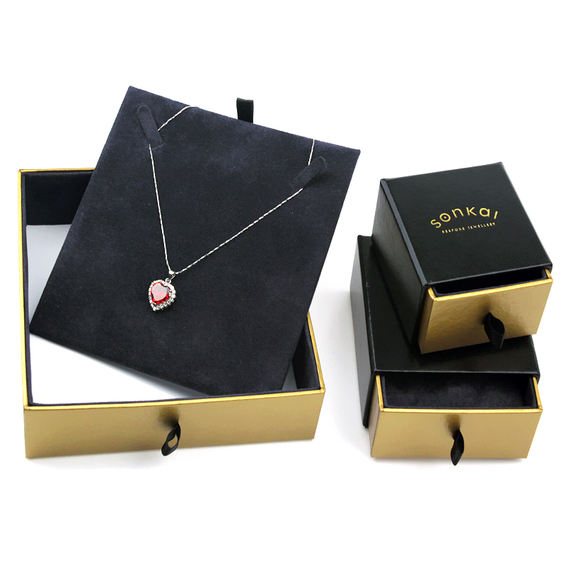 Open two-tier drawer jewelry box with black velvet interior and gold-trimmed edges, featuring a heart-shaped pendant necklace displayed on a custom insert, showcasing premium packaging design.