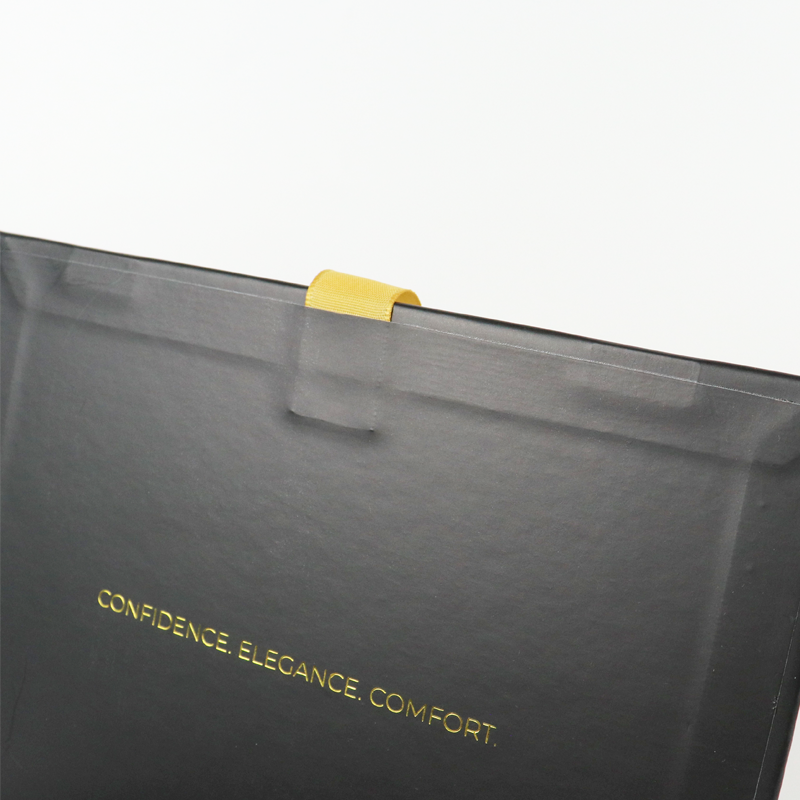 Close-up of a black box corner with a yellow pull tab and gold text reading "CONFIDENCE. ELEGANCE. COMFORT." printed on the surface.
