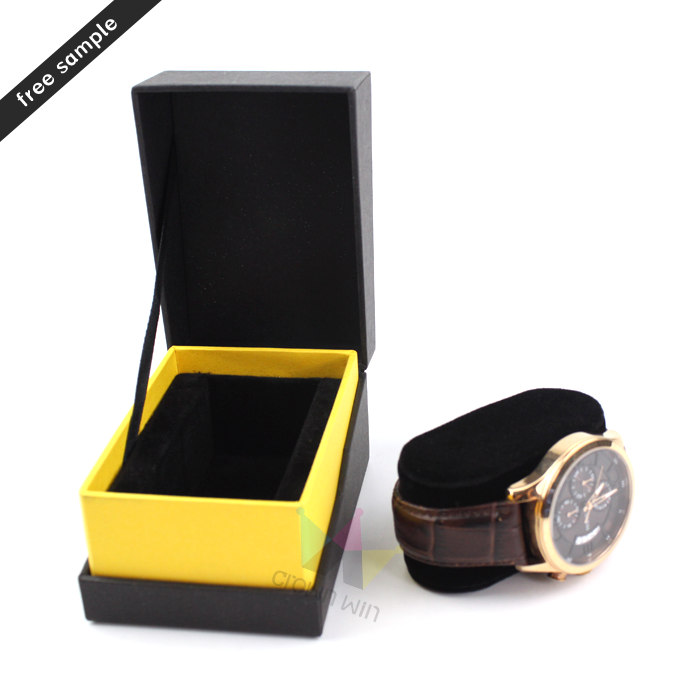 Black rigid watch box with vibrant yellow interior and black ribbon closure, showcasing a gold-tone watch with brown leather strap—ideal for modern lifestyle brands.