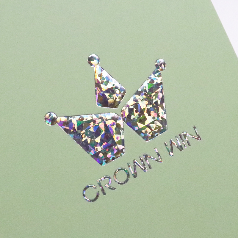 Holographic crown-shaped logo with "CROWN WIN" text on a pastel green background, featuring iridescent reflective effects.