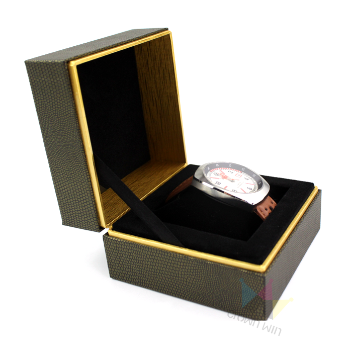 Brown textured rigid watch box with gold edges and black velvet lining, housing a silver watch with brown leather strap—showcasing elegant packaging for mid-luxury brands.