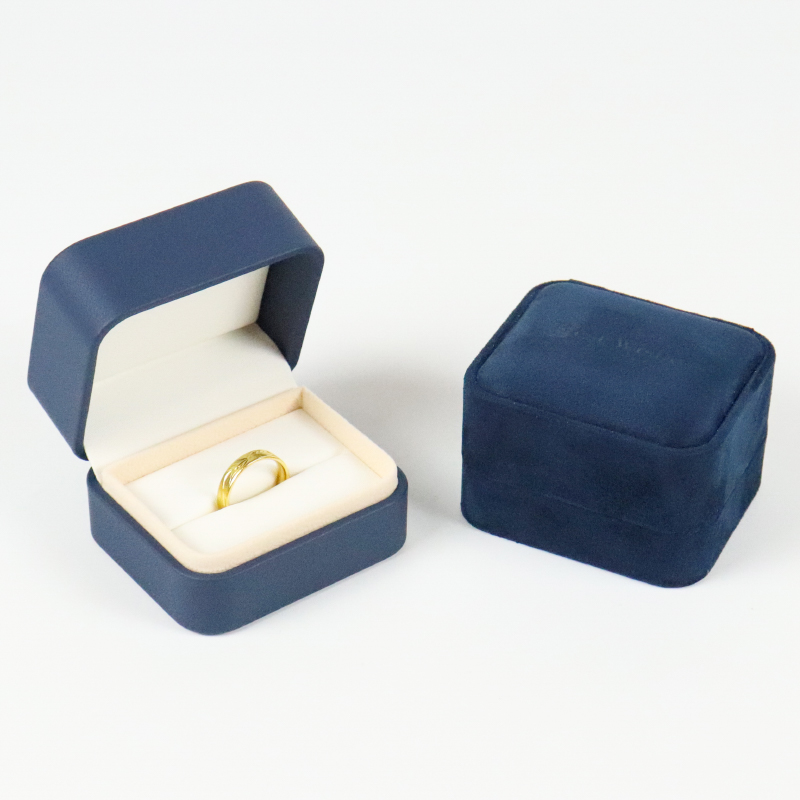 Open blue velvet ring box showing a gold wedding band resting in a cream-colored felt insert, emphasizing elegance and precision.
