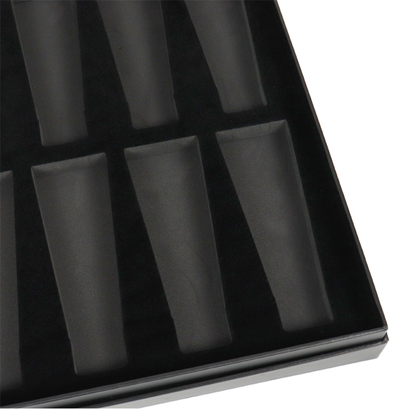 Close-up of a black foam tray featuring multiple precisely cut compartments, ideal for storing earrings or small accessories.