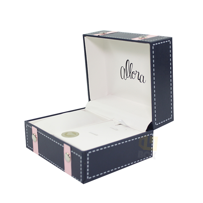 Open navy blue box with pink straps and silver rivets, featuring branded interior lining with "allora" script and clean compartments.