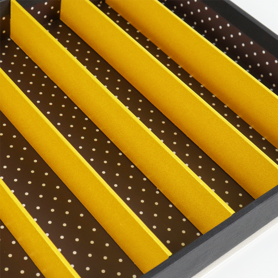 Close-up view of yellow paperboard dividers inside a tray, designed to separate and stabilize multiple vape cartridges during shipping.