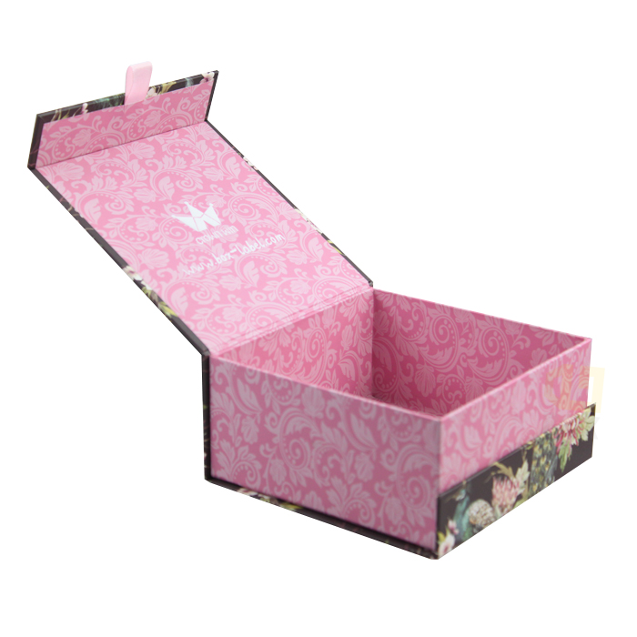 Open pink box with floral pattern on exterior and swirling damask design inside, featuring a white logo and website text on the lid.