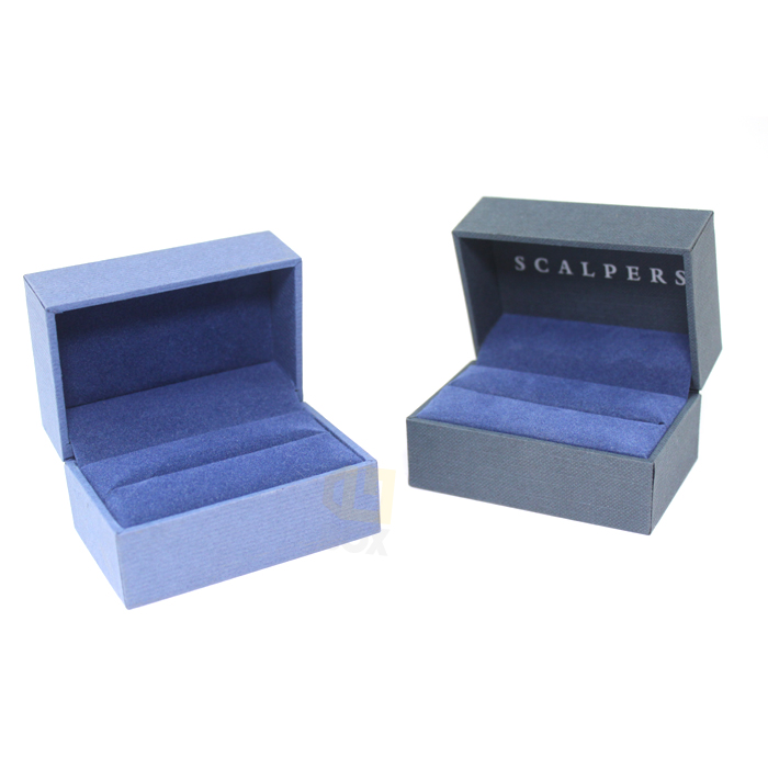 Two open blue ring boxes with soft velvet lining; one features embossed "SCALPERS" branding on the lid, both showing narrow, precise slots for ring placement.