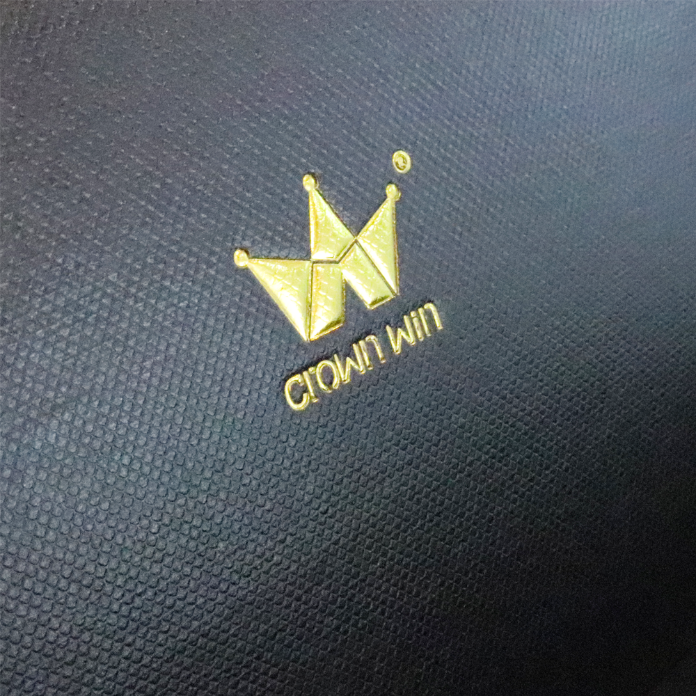 Close-up of a gold foil-stamped crown logo on a dark textured background, highlighting sharp edges and reflective finish.