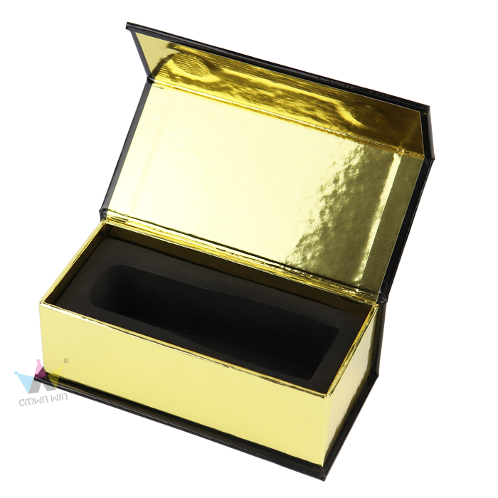 Open gold foil box with black interior and custom-shaped foam insert, showcasing reflective surface and precise cavity design.